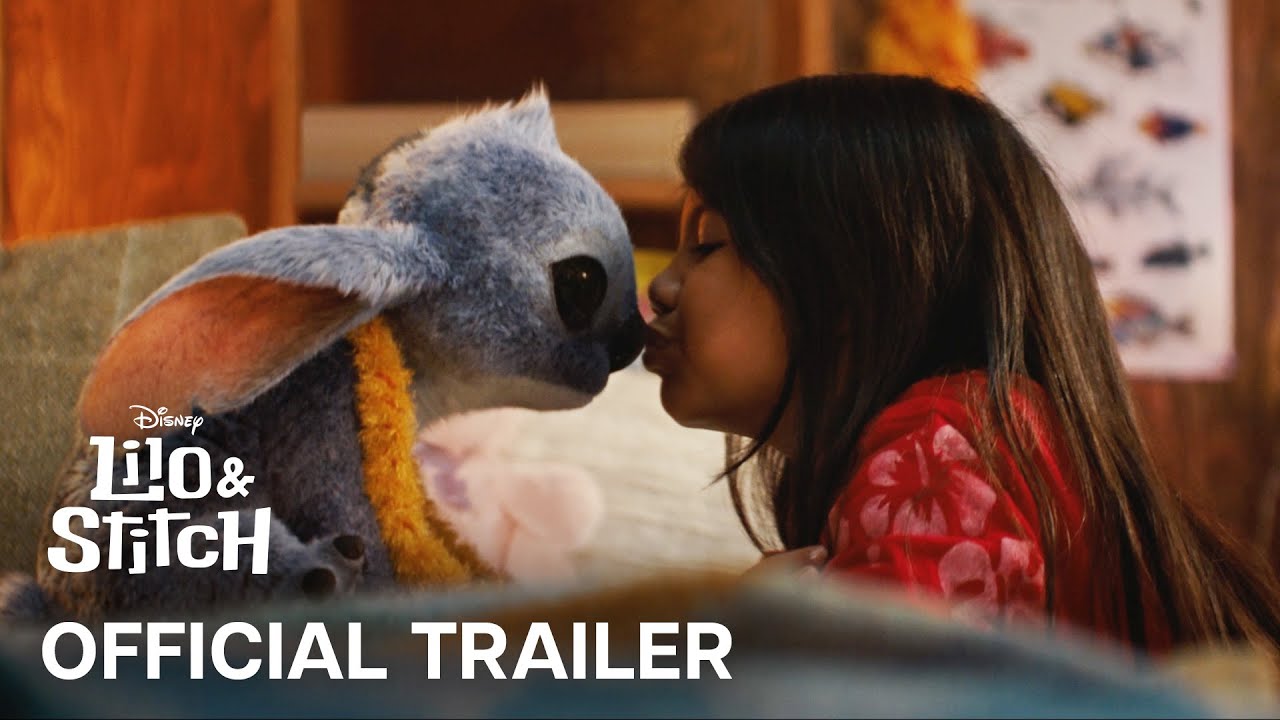 This image shows the character Lilo kissing Stitch on his nose, with the text "Lilo and Stitch Official Trailer" over top of it.